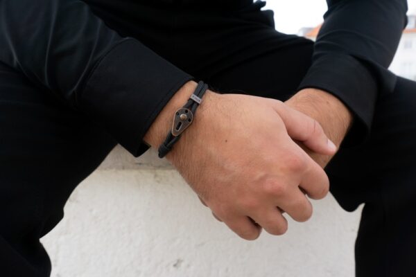 Poignet d'homme portant plusieurs bracelets en cuir et métal superposés