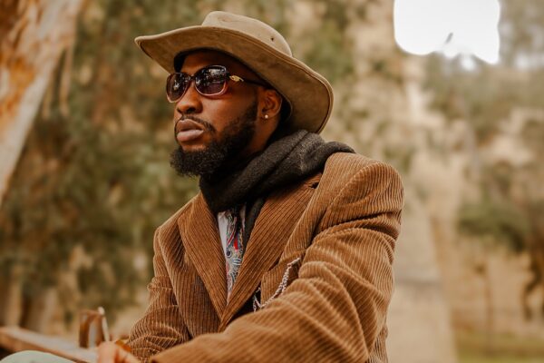 Homme en tenue d'automne superposant un trench camel, un pull en maille et une écharpe