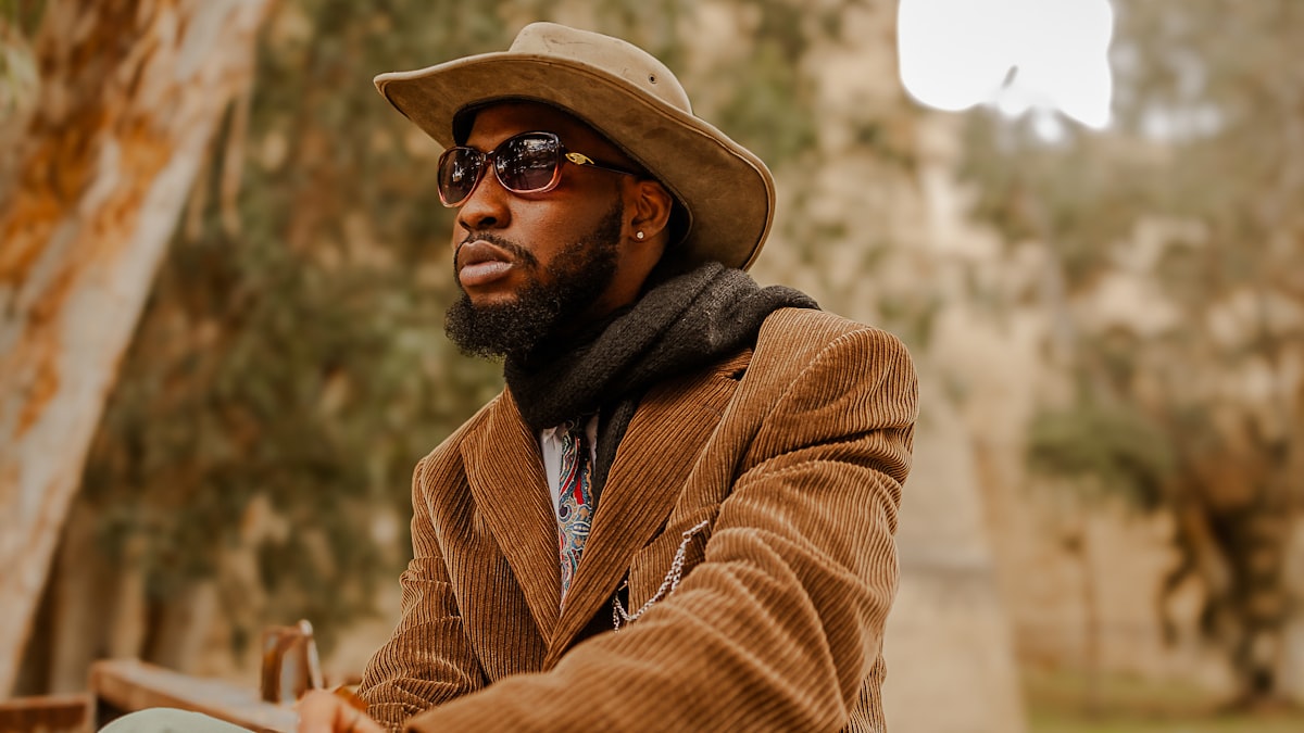 Homme en tenue d'automne superposant un trench camel, un pull en maille et une écharpe